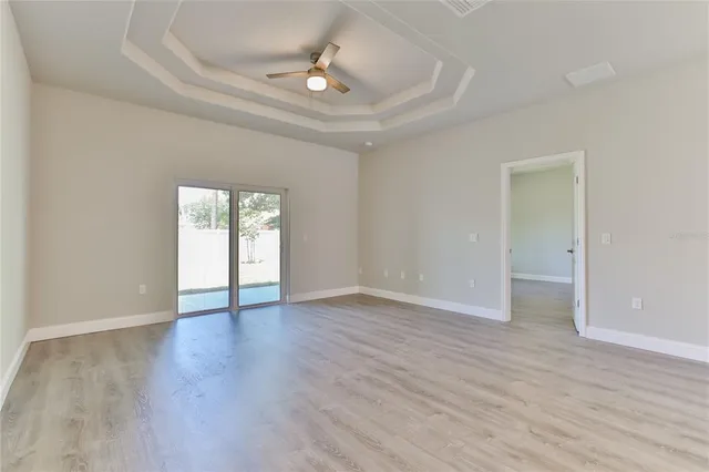 a view of an empty room with window and wooden floor