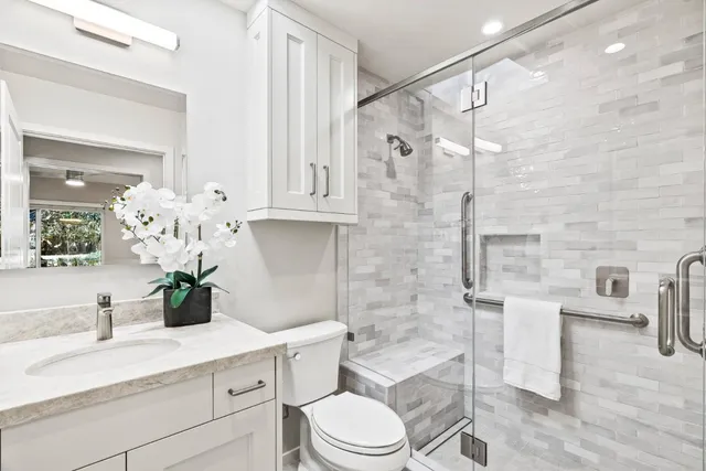 a bathroom with a granite countertop sink a toilet and a mirror