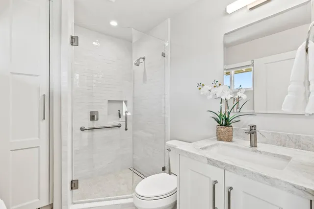 a bathroom with a granite countertop sink a toilet and shower