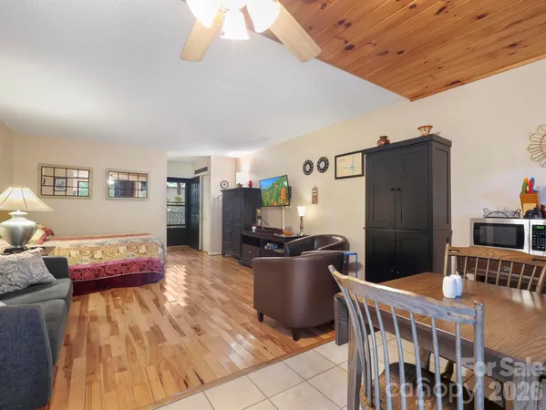 a kitchen with stainless steel appliances kitchen island granite countertop a refrigerator a stove a dining table and chairs with wooden floor