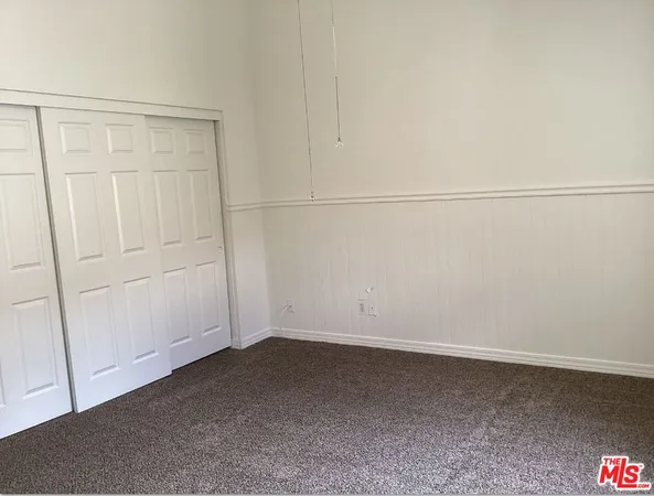 an empty room with windows and chandelier fan