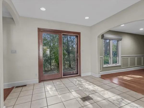 a view of an empty room with window and chandelier fan