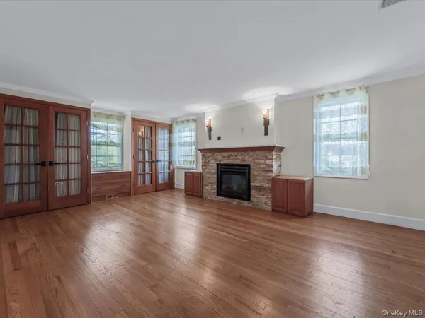 an empty room with wooden floor fireplace and windows
