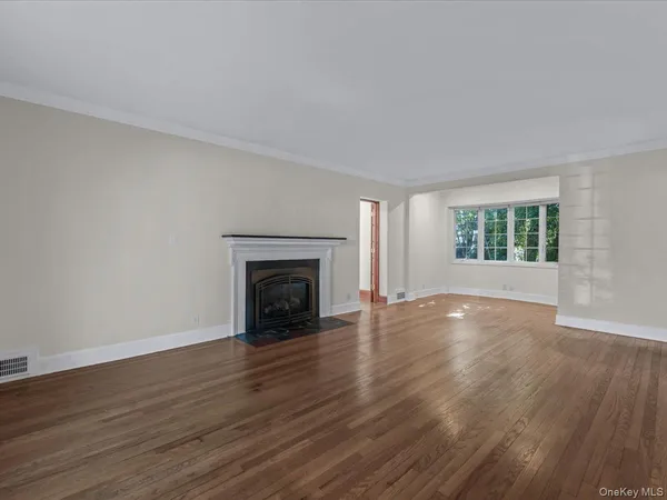 an empty room with wooden floor fireplace and windows