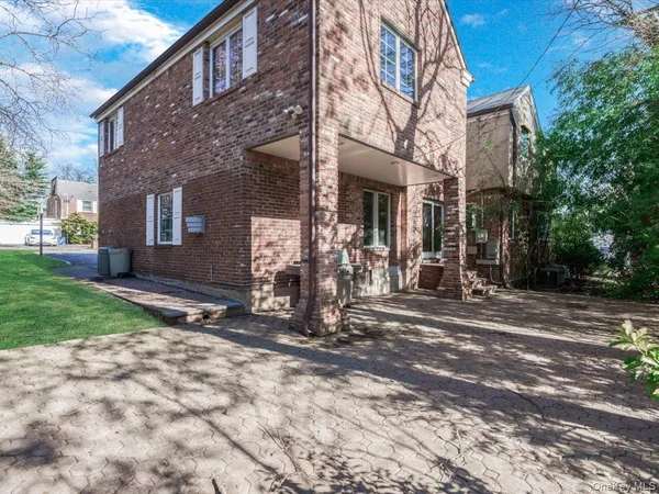 a view of a house with brick walls plants and a large tree