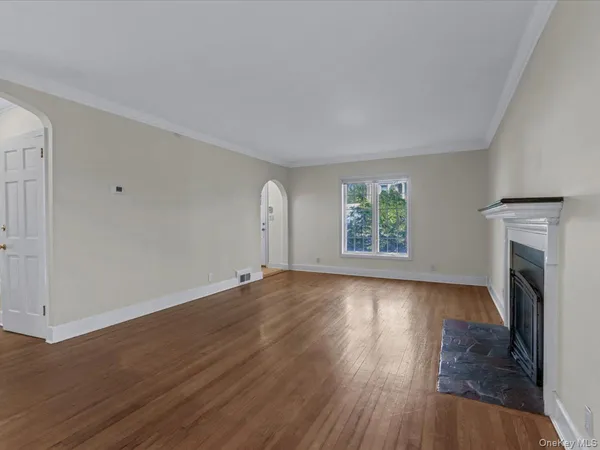 an empty room with wooden floor fireplace and windows