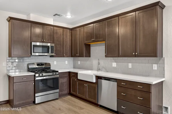 a kitchen with granite countertop stainless steel appliances a sink stove and cabinets