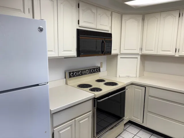 a kitchen with granite countertop white cabinets and black appliances