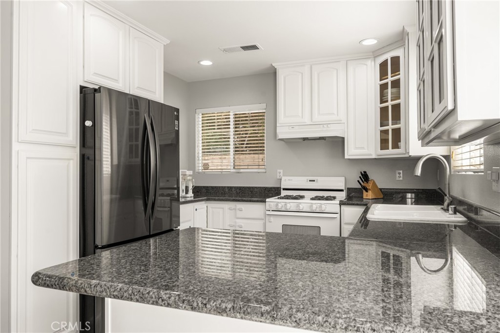 418 East Olive Avenue, Unit B Monrovia, CA 91016 - Photo 13 of 40 a kitchen with stainless steel appliances granite countertop a refrigerator a stove a sink a dining table and chairs