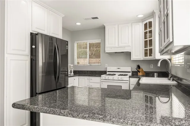 a kitchen with stainless steel appliances granite countertop a refrigerator a stove a sink a dining table and chairs