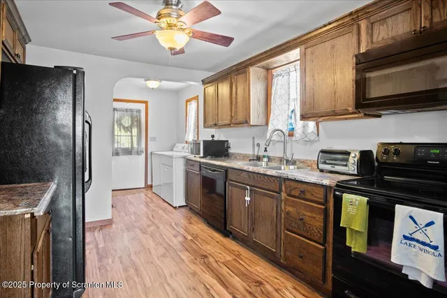 a kitchen with a sink stainless steel appliances cabinets and a window