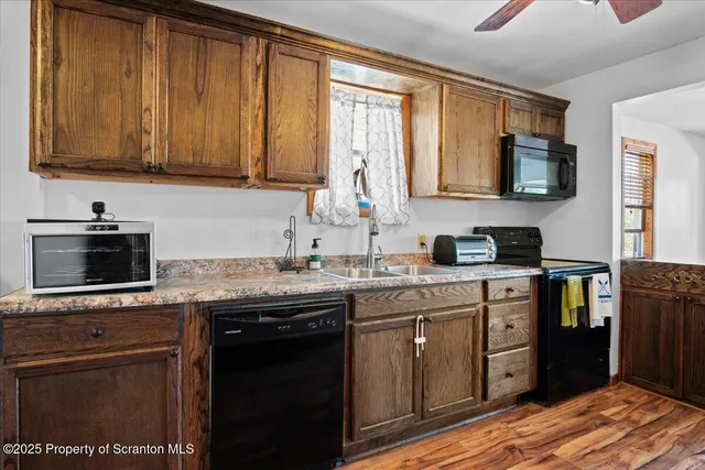 a kitchen with stainless steel appliances granite countertop a stove a sink dishwasher and a microwave oven with wooden cabinets