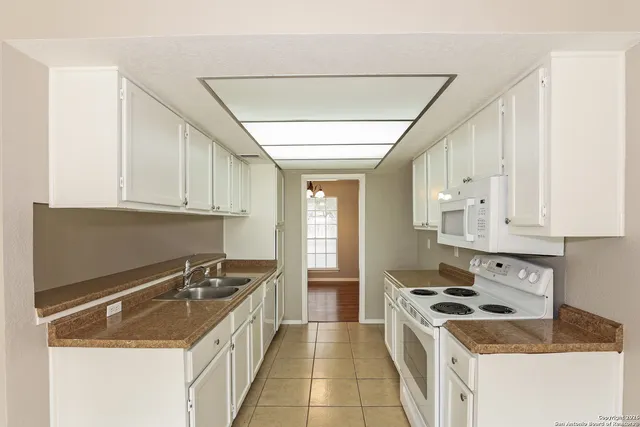a kitchen with granite countertop a sink stove and cabinets