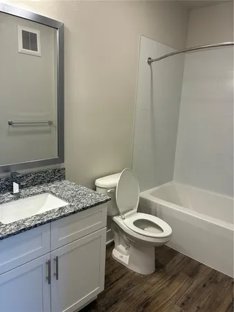 a bathroom with a granite countertop toilet sink and mirror