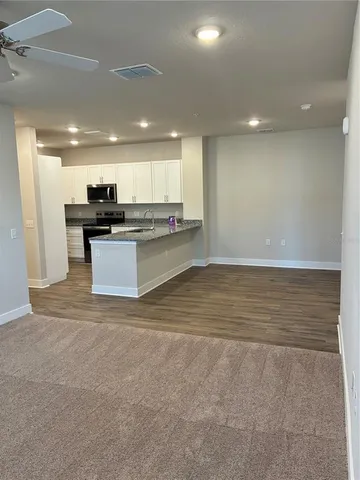 a view of kitchen with kitchen island a sink wooden floor and a refrigerator