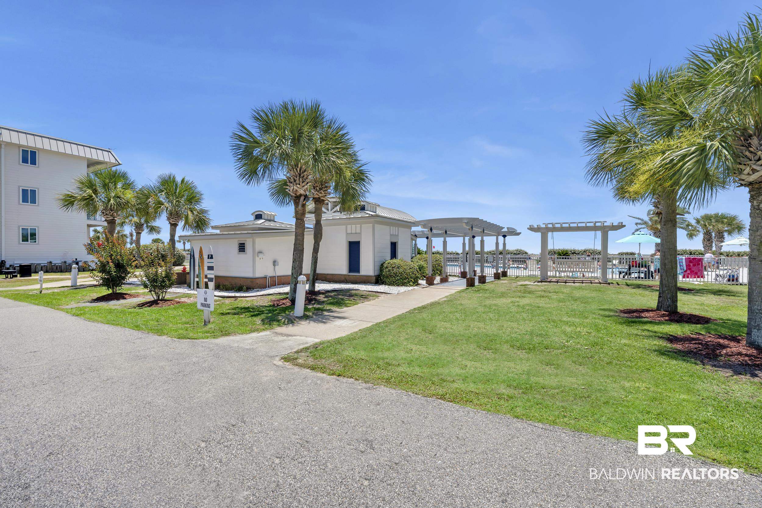 400 Plantation Road, Unit 2118 Gulf Shores, AL 36542 - Photo 25 of 59 Community grounds featuring a paved pathway, manicured lawn, multiple palm trees, and a white pergola structure
