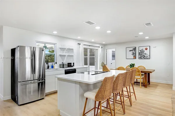 a kitchen with stainless steel appliances a dining table chairs and refrigerator