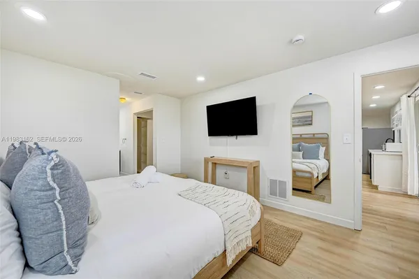 a spacious bedroom with a bed and a flat screen tv
