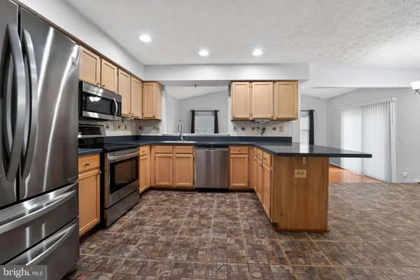 a kitchen with stainless steel appliances granite countertop a refrigerator and a stove top oven