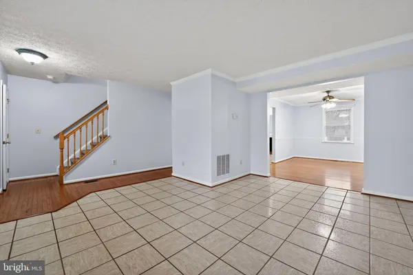 a view of an empty room with wooden floor and a ceiling fan