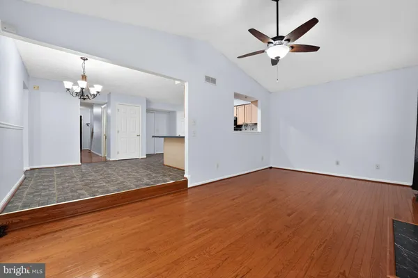 a view of an empty room with wooden floor fireplace and a window