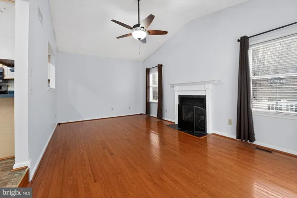 a view of an empty room with wooden floor fireplace and a window