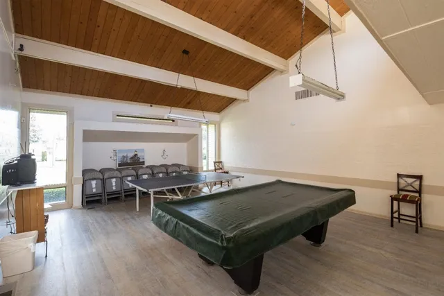 a living room with furniture pool table wooden floor and windows