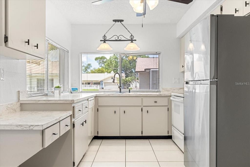 13013 Sawmill Way Hudson, FL 34667 - Photo 14 of 33 a kitchen with granite countertop white cabinets white appliances a sink and a large window