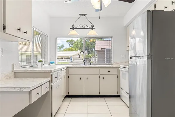 a kitchen with white cabinets and window