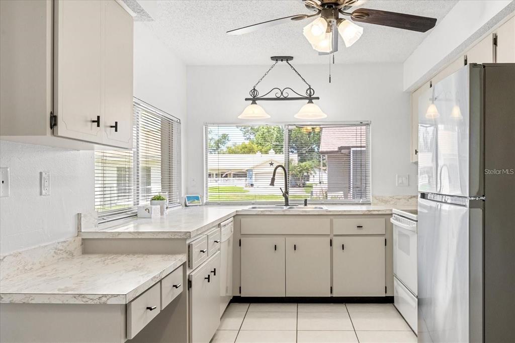 13013 Sawmill Way Hudson, FL 34667 - Photo 17 of 33 a kitchen with a sink dishwasher a stove and white cabinets
