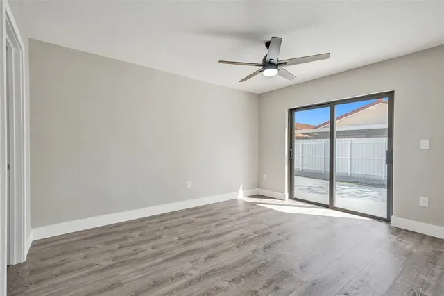 an empty room with wooden floor fan and windows