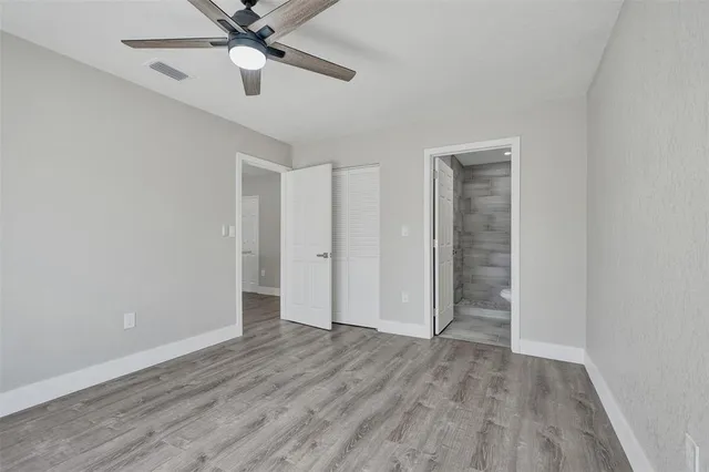 an empty room with wooden floor fan and windows