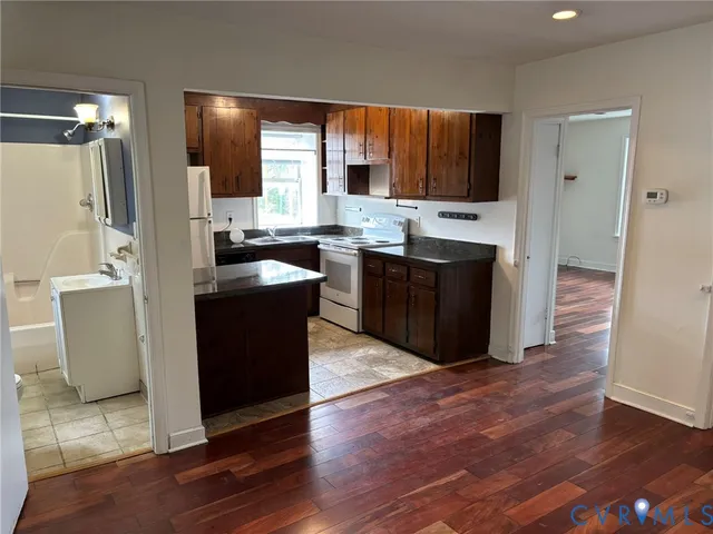 a kitchen with granite countertop a refrigerator stove and sink