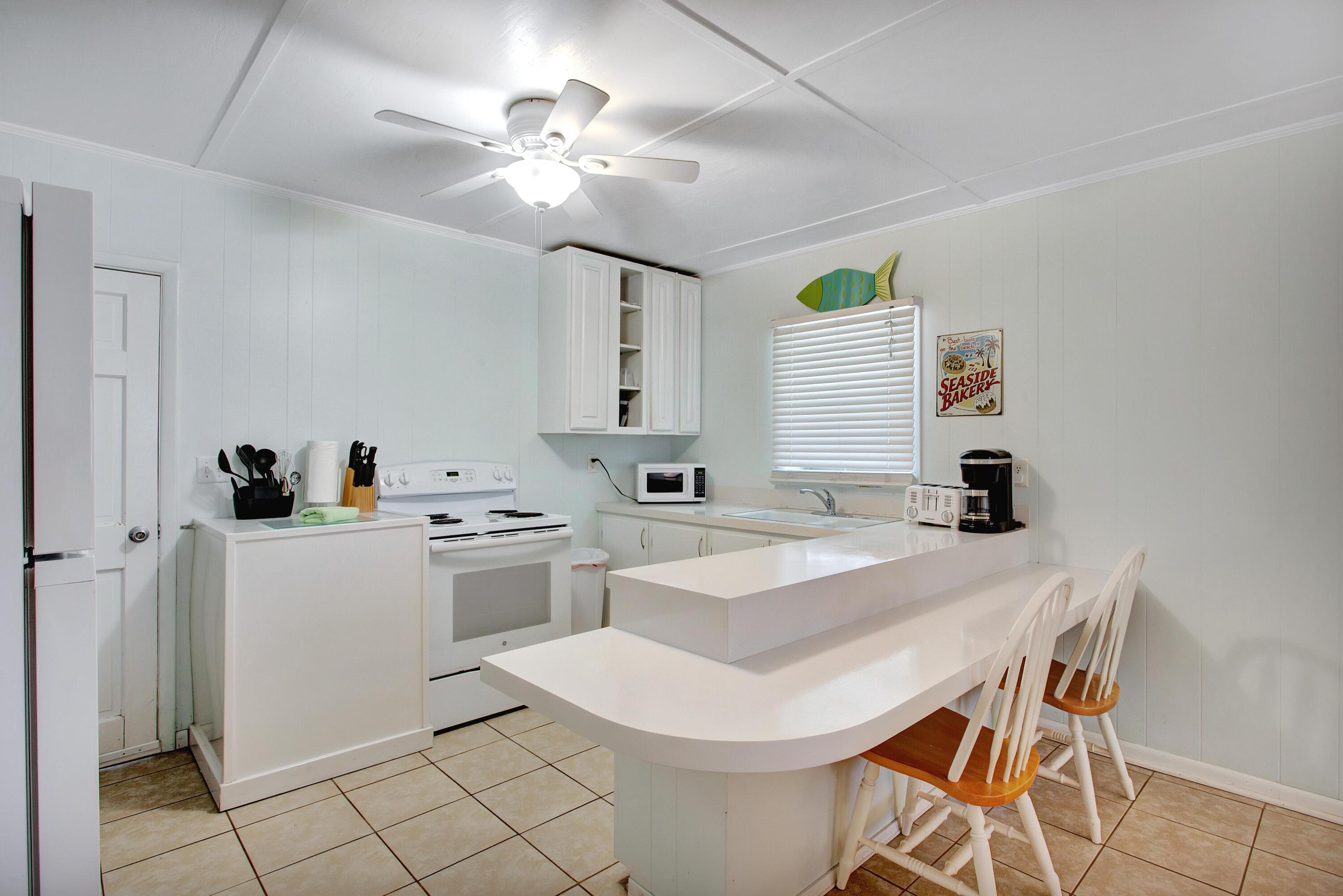 545 Blue Mountain Road Santa Rosa Beach, FL 32459 - Photo 9 of 27 a kitchen that has a sink a stove and chairs with wooden floor