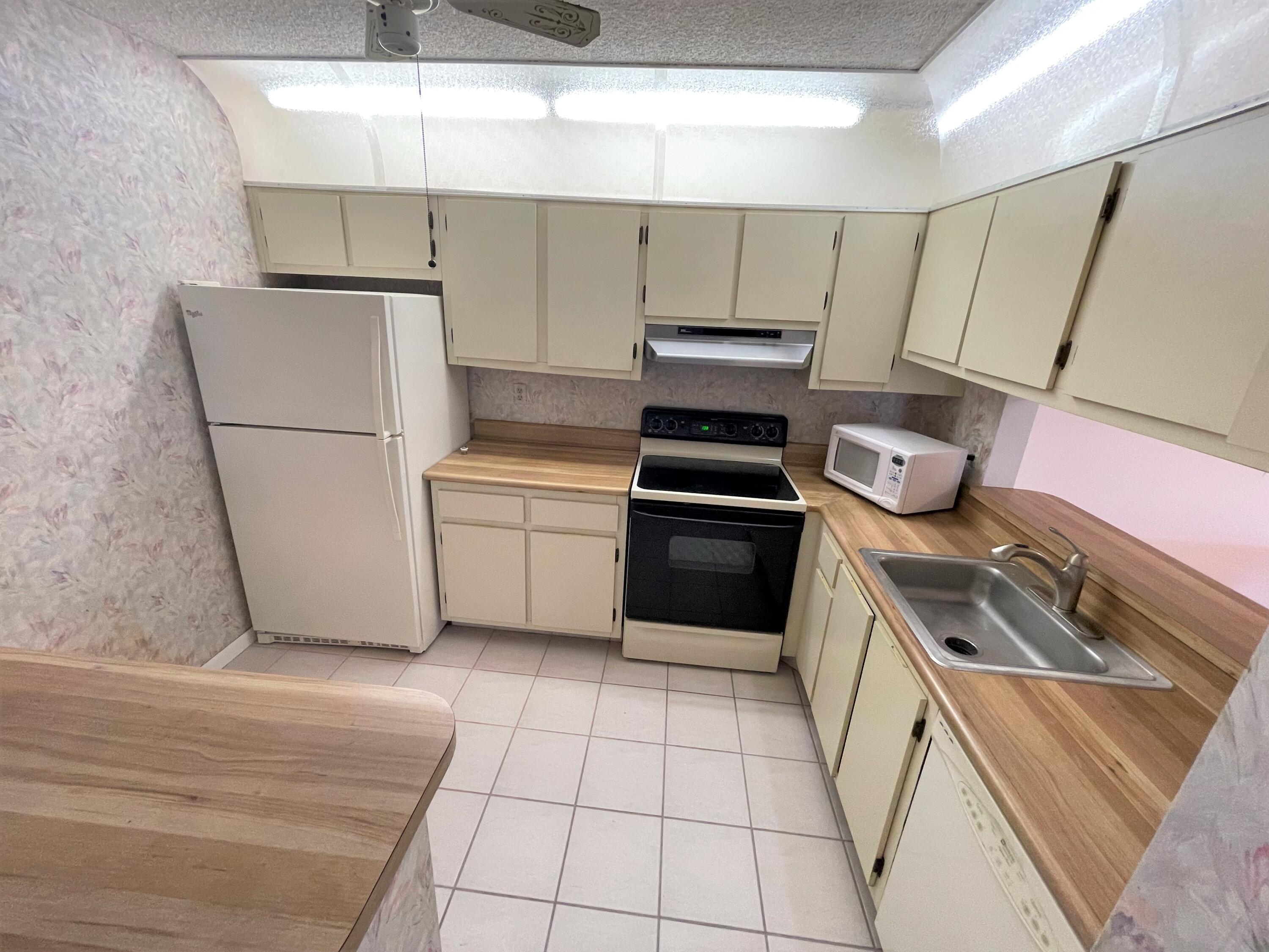 6485 Chasewood Drive, Unit C Jupiter, FL 33458 - Photo 9 of 23 a kitchen with a stove a sink and a refrigerator