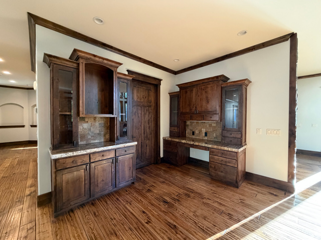 4536 North 475 East Provo, UT 84604 - Photo 31 of 65 Custom built-in cabinetry and desk area featuring wood-finish flooring, stone countertops, and tile backsplash