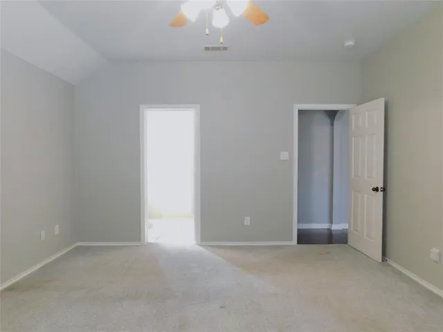 an empty room with a ceiling fan and window