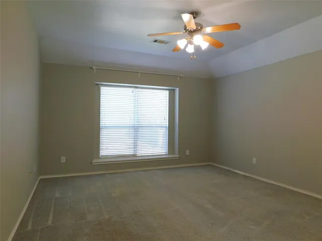 an empty room with a chandelier fan and windows