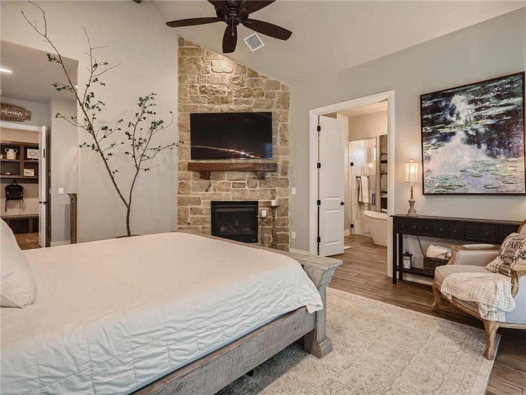 132 Huerta Road Florence, TX 76527 - Photo 13 of 40 A rustic stone fireplace anchors this primary bedroom, offering warmth and direct access to a spa-like bathroom.