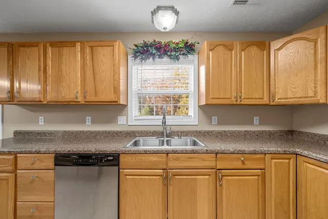 a kitchen with granite countertop cabinets stainless steel appliances a sink and a window