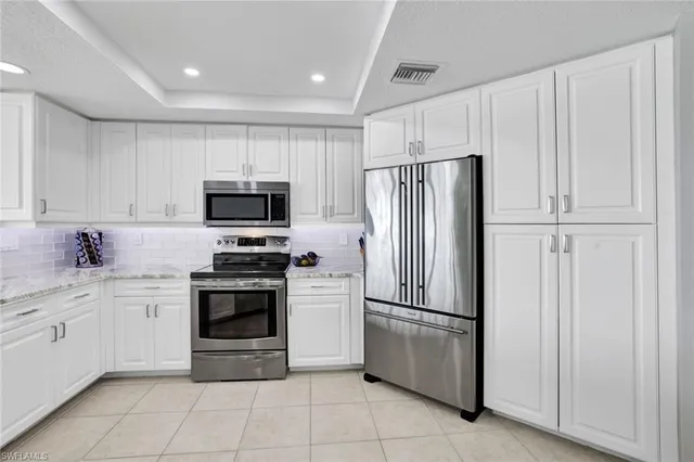 a kitchen with stainless steel appliances granite countertop a refrigerator sink and white cabinets
