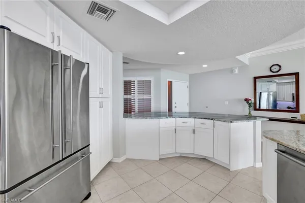 a kitchen with granite countertop white cabinets and refrigerator