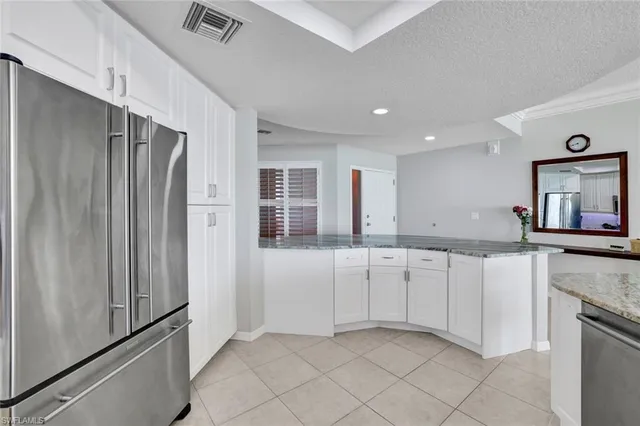 a kitchen with granite countertop white cabinets and refrigerator