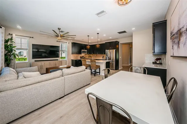 a kitchen with stainless steel appliances kitchen island granite countertop a refrigerator a stove a sink dishwasher and a microwave with wooden floor