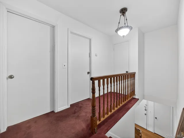 a view of an empty room with wooden floor and stairs