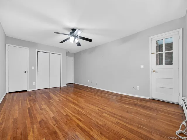 a view of an empty room with a window and wooden floor