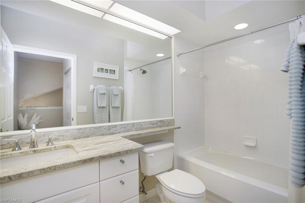 23821 Marbella Bay Road, Unit 202 Estero, FL 34135 - Photo 15 of 42 a bathroom with a granite countertop bathtub shower sink vanity mirror and toilet