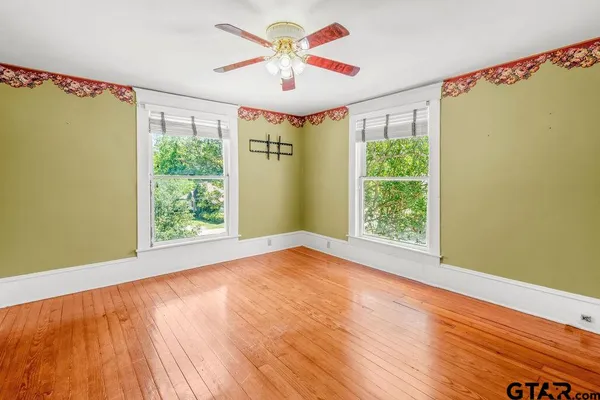 a view of a big room with wooden floor and windows