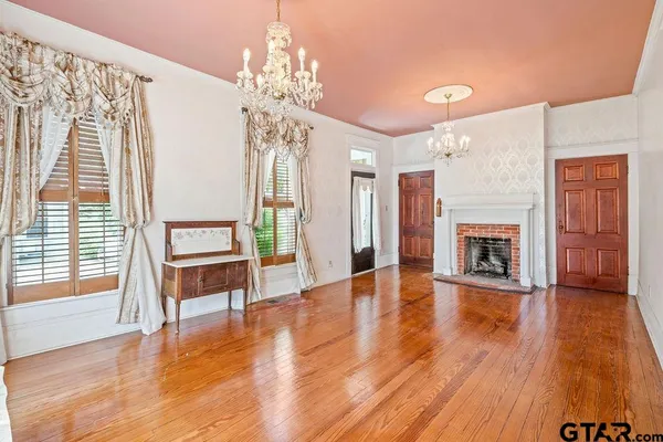 a view of a livingroom with furniture wooden floor fireplace and windows