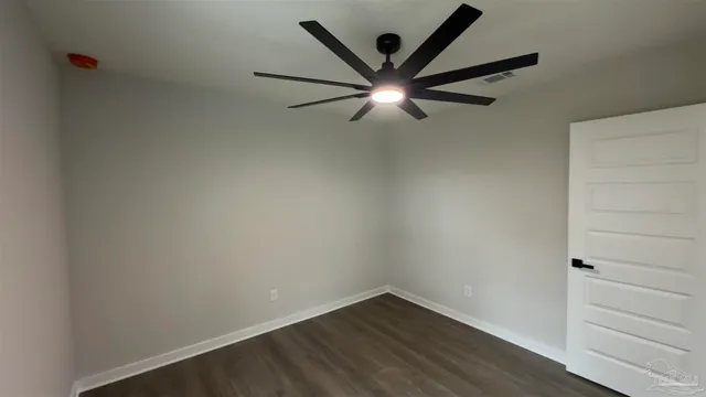 an empty room with wooden floor and a ceiling fan